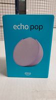 Front view of Echo Pop retail box in teal color showing speaker image and branding.