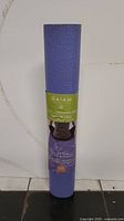 Front view of the rolled purple yoga mat showing the Gaiam label and Ash Leaves branding.