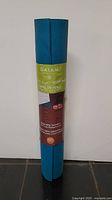 Front view of rolled blue yoga mat with Gaiam Earth & Sky paper label.