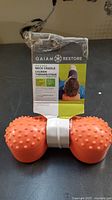 Front view showing product packaging and orange textured neck cradle with raised nodules.