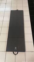 Image of unfolded dark grey tri-fold foam mat with visible cut and dirt near Gaiam logo on surface, showing full length and width.