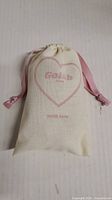 Closed cream drawstring bag with pink ribbon and Golâb branding in a heart shape with the phrase 'with love'.