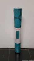 Front view of Jogi turquoise patterned yoga mat, rolled and shrink-wrapped.