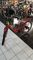 Front view of red electric bike with basket and visible missing seat, showing the Daymak logo on the frame.