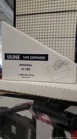 Side view of the box showing Uline branding, product type, and model number H-150 on a white triangular box with graphic of the tape dispenser on top of a box.