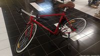 Red Vermont electric bicycle on black tiled floor with white rims and brown leather seat.