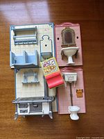 Top-down view of different Playmobil dollhouse furniture pieces including kitchen and bathroom items such as stove, sink, toilet, shelves