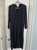 Full view of the long black dress showing the length, buttons, and silhouette.