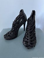 Front angle of black Aldo women's heeled sandals with knotted and twisted strap design and peep toes.
