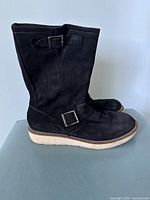 Side view of black suede women's boots showing upper material, buckle, and sole.