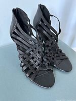 Front top view of pair of black woven strap leather heeled sandals as shown from above.