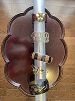 Photo of five assorted bracelets displayed on a light grey cylindrical holder over a scalloped dark wooden tray.