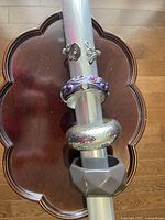 Four bracelets displayed on a clear cylindrical stand on a wooden table.