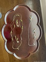 Photo showing two bead necklaces and matching pairs of earrings placed on wooden tray