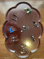 Photo shows seven pairs of mixed style earrings arranged on a wooden surface with metal hooks and various colored beads and pendants.