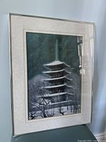 Framed print of a Japanese pagoda surrounded by snow-covered trees under a moody sky.