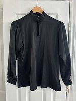 Full view of the black silk blouse on a hanger showing mandarin collar, long sleeves with buttoned cuffs, and front keyhole detail.