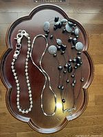 Top view of three necklaces on a wooden tray, showing details of chains and beads