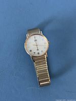 Front view of Timex watch showing white dial with gold-tone hour markers and stretch band.