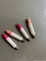 Four antique milk glass candle-shaped Christmas light bulbs with colored flame tips, laid on a flat surface.