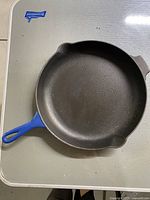 Top view of blue Le Creuset cast iron pan showing black cooking surface and blue handle