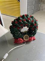 Front view of ceramic Christmas wreath with attached power cord
