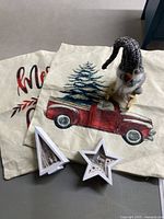 Three Christmas pillow covers and two white wooden LED light-up ornaments and knit Santa gnome figurine displayed together