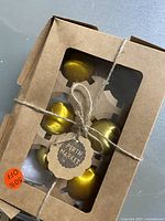 Boxed set of eight gold-colored Christmas ornaments, tied with string and tagged 'Perth Market' with a 50% off sticker visible.