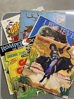 Photo of a stack of approximately 8 vintage vinyl records with colorful album covers. Visible titles include a cowboy on a bull, Christmas theme, I Believe with woman illustration, and Romper Room TV Nursery. Some price stickers are visible on covers.