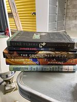 Stack of five mystery/thriller books showing spines with titles and authors clearly readable.