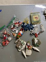 Photo showing a variety of vintage wooden Christmas ornaments laid on a flat surface, including Santa figurines, stars, bells, snowman, and animals.
