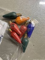 Seven vintage Christmas bulbs in assorted colors sealed in a clear plastic bag on a flat surface.