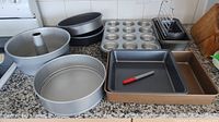Assorted pans arranged on counter including muffin, loaf, square, round and tube pans