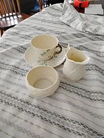 Cup, saucer, creamer and bowl displayed on cloth