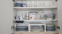 Cabinet view showing plates, bowls, glasses, teapot