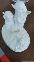 front view of porcelain nativity figurine with two angels and Baby Jesus