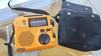 Front view of orange Grundig FR-200 radio beside black case