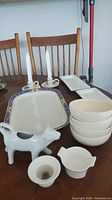 Group shot of platter, cow creamer, bowls, candlesticks, funnel strainer, pour bowl