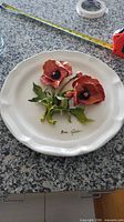 Full view of porcelain plate with poppy flowers and measuring tape