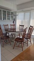 Full dining set: round table and six of eight chairs visible