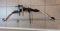 Right-side view of Hoyt compound bow showing sight, rest and stabilizer on tile floor