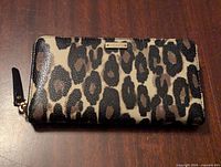 Photo of the wallet front side showing leopard print pattern and Kate Spade logo plaque.