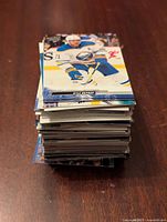 Stack of hockey cards showing player Kyle Okposo on the top card in action wearing a white and blue jersey.