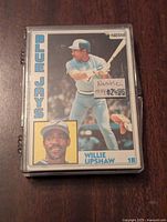 Front of Willie Upshaw baseball card in protective case, showing player in batting pose and inset portrait with team name on side.