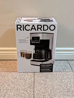 Front and side view of boxed Ricardo programmable coffee maker showing brand name, product image, and key features.