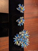 Front view of Sherman blue rhinestone brooch and matching clip-on earrings showing detailed floral design and vibrant blue stones.