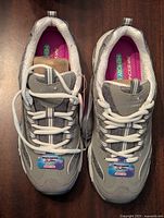 Top-down photo of the pair of new grey Skechers D'Lites sneakers with white laces, showing shoe tongue logo and memory foam insole branding.