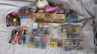 Wide shot showing the full collection of various kids toys including packaged and loose Mashems toys, action figures, small character toys, and a plush robot dog in box.