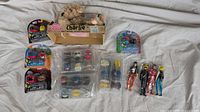 Lot of toys including Robot Dog plush, Mashems, and action figures arranged on white sheet.