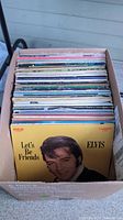 Box of multiple vinyl records including visible cover of Elvis Presley's "Let's Be Friends"